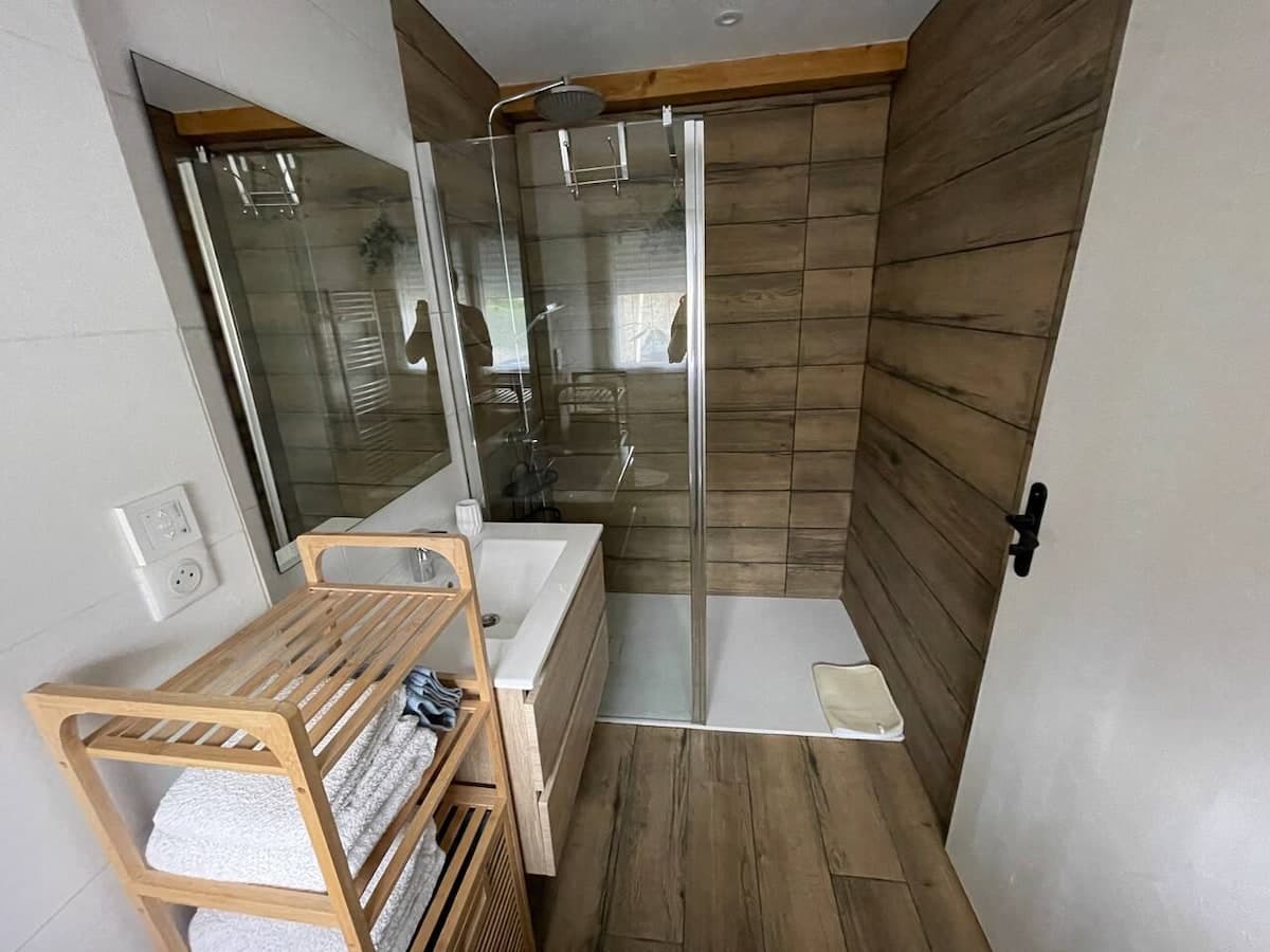 Douche à l'italienne derrière une paroi vitrée, mur en bois