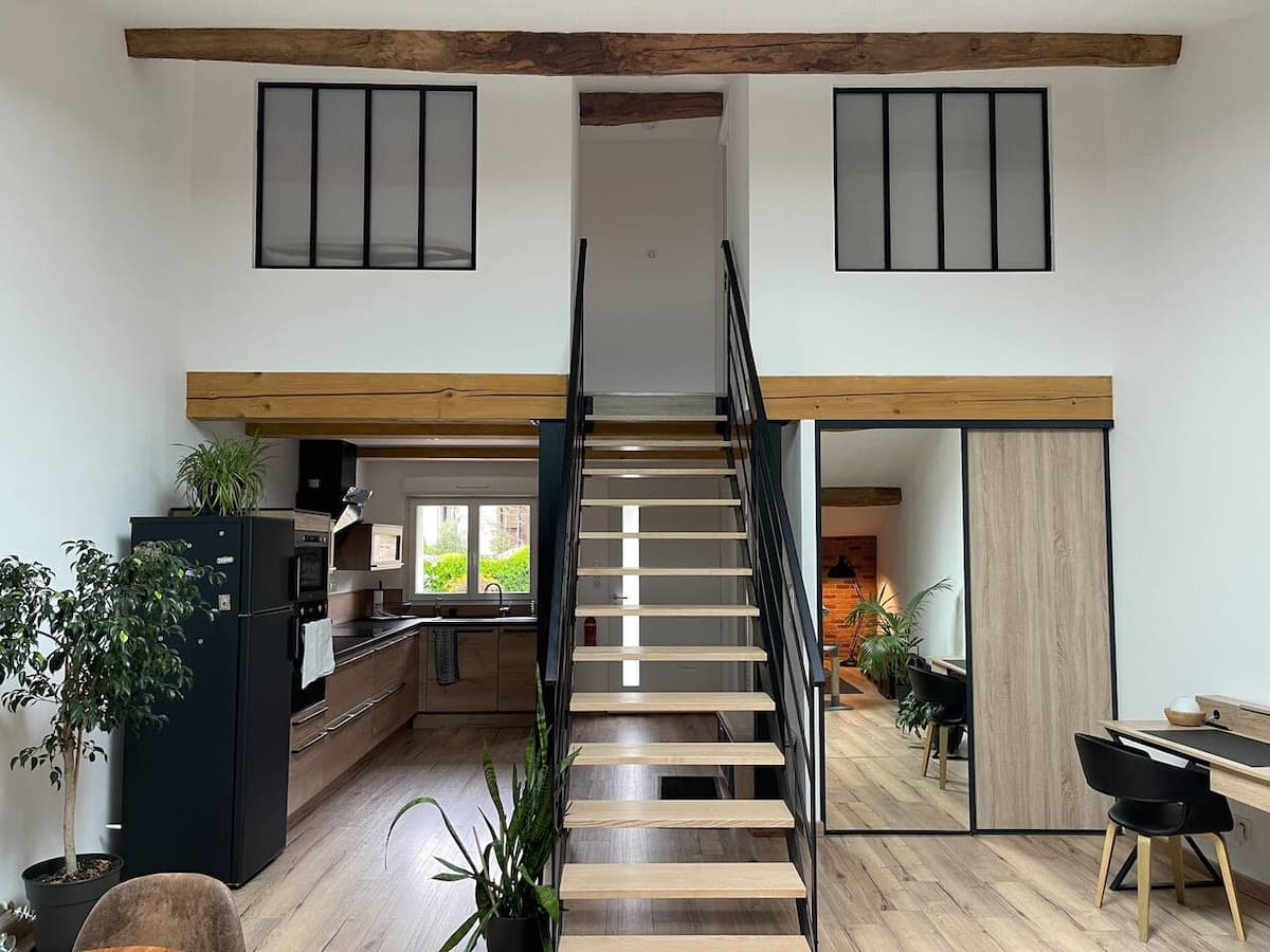 Black metal staircase up to the mezzanine, between two glass partitions